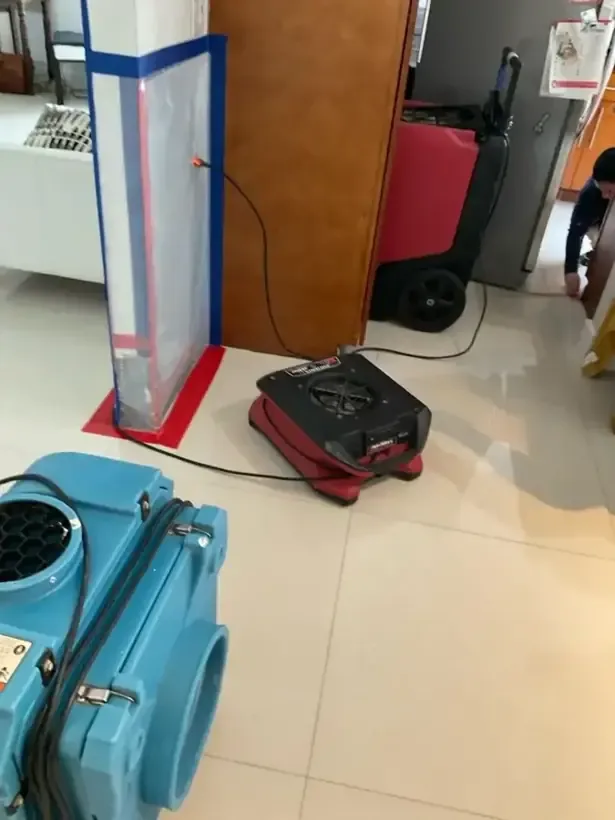Containment doorway beside an air scrubber and a dehumidifier inside a house