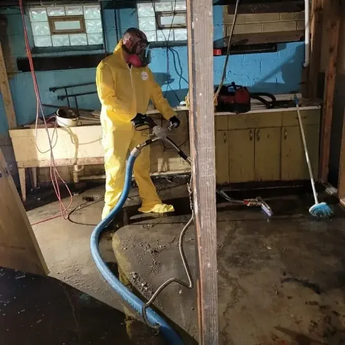 Worker in yellow protective clothing using extraction equipment on an exposed floor